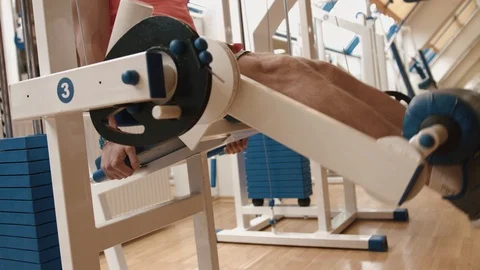 Unknown man athlete is training at the leg curl trainer. Close-up view. 4k. Work Stock Footage 93040390