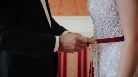 An unknown man as usual someone from close family ties a red ribbon around the Stock Footage 234546644