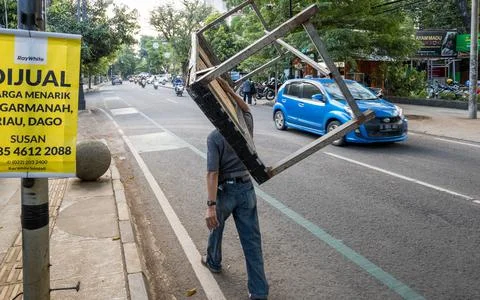 An unknown man walked while hauling a table over his shoulder Stock Photos