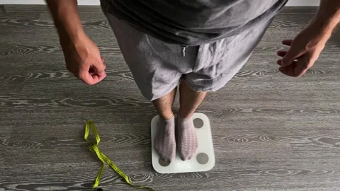 An unknown man who has lost weight is weighing himself. View from above. Stock Footage 283924180