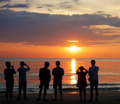 Unknown people watching sunset at the beach. Stock Photos