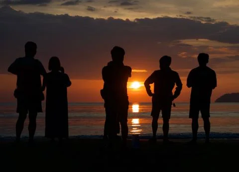 Unknown people watching sunset at the beach. Stock Photos