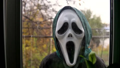 An unknown person appears outside the window wearing a screaming mask. Maniac in Stock Footage 163779163