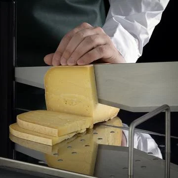 Unknown person cuts cheese using a cheese slicer Stock Photos