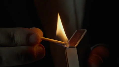 Unknown person striking match on side of box dark isolated closeup. Fire appear Stock Footage 332508591