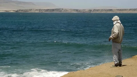 Unknown Peruvian man pending on breakwater in Paracas, Peru Stock Footage 125277293