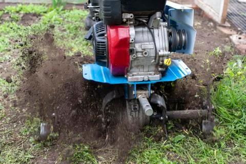 The unknown plows the earth with the help of a motor-block Stock Photos