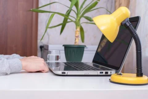 Unknown sitting at a white table in front of the laptop is idle Stock Photos