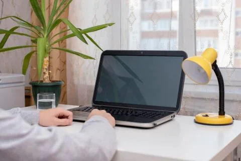 Unknown sitting at a white table in front of the laptop is idle Stock Photos