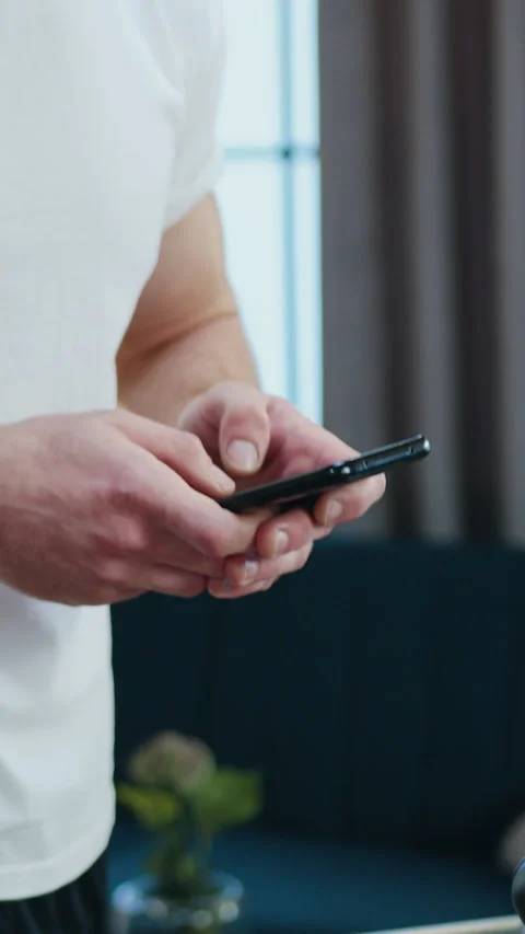 Unknown strong active sporty man uses his phone during morning home workout on r Stock Footage 328592115