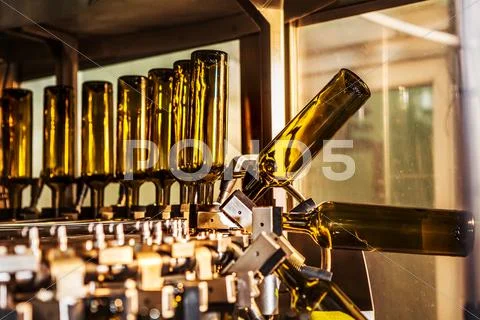 Unlabeled glass bottles in bottling machine at modern winery Stock Photos