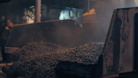 Unloading the asphalt mixture into an asphalt paver. Repair of a city road at Stock-Footage 153380392