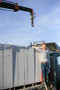 Unloading building blocks from a truck using a crane. Hydraulic manipulator. Stock Photos