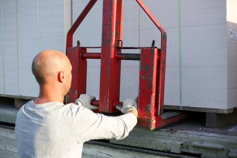 Unloading building blocks from a truck using a crane. Hydraulic manipulator. Stock Photos