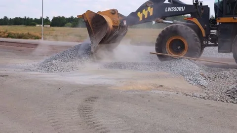 Unloading of crushed stone on road with heavy machinery. Stock Footage 230162907
