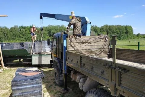 Unloading the front brick using a mobile crane in the village in private terr Fotos de archivo