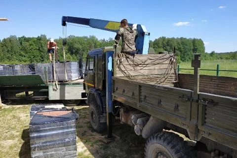 Unloading the front brick using a mobile crane in the village in private terr Stock Photos