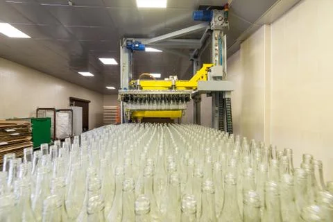 Unloading glass bottles with an automatic machine. Stock Photos