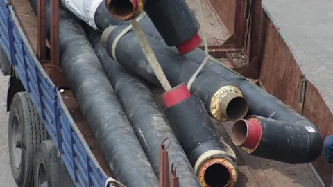 Unloading insulated pipeline sections from flatbed truck bed transporting Video stock 342922359