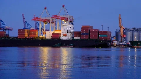 Unloading a merchant ship at dusk of the day in the seaport Stock Footage 98030839