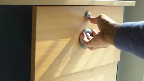 Unlocking and pulling open wooden drawer with black round handle revealing .. Stock Footage 332746664