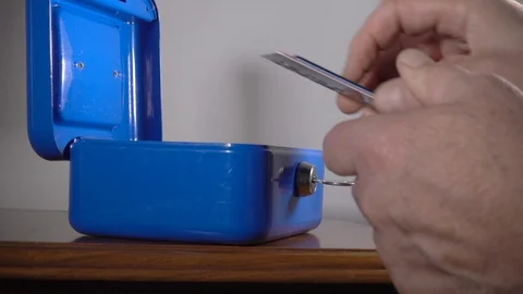 Unlocking a personal security box then putting credit cards inside. Video stock 114077445