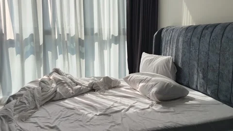 Unmade Bed with Crumpled White Sheets in Morning Light Vídeos de archivo 342889713