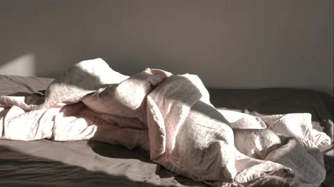 Unmade bed, falling light from a window moving along the wall. Video stock 131369972