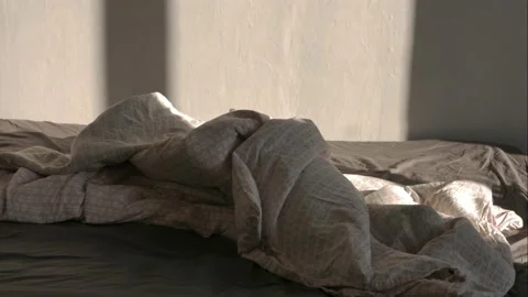 Unmade bed, falling light from a window moving along the wall. Stock Footage 131369999