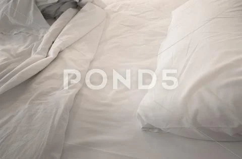 An unmade bed with white linens Stock Photos