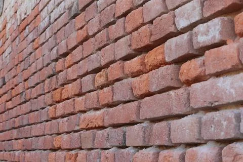 Unmaintained old brick wall made of orange old broken bricks Stock Photos