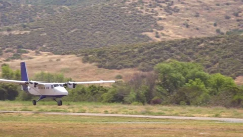 An unmarked twin engine plane takes off from a dirt airstrip. Stock Footage