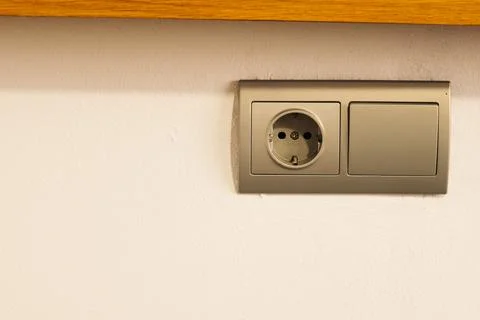 Unoccupied grey socket on the white wall. Stock Photos