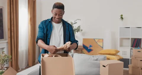 Unpacking cardboard boxes after moving, man cleans new apartment cluttered with 動画素材 170345641