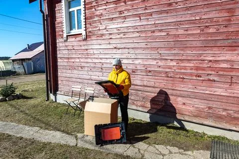 Unpacking modular compost bin from cardboard box near wooden house in rural.. Stock Photos