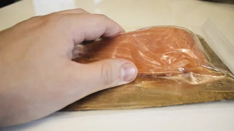 Unpacking red fish from a vacuum package. Man shows fish close up Stock Footage 126596733