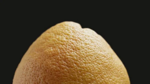 Unpeeled grapefruit rotating at black background. Grapefruit peel texture. 库存影片 329937481