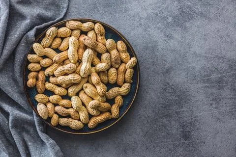 Unpeeled peanuts on kitchen table. Stock Photos