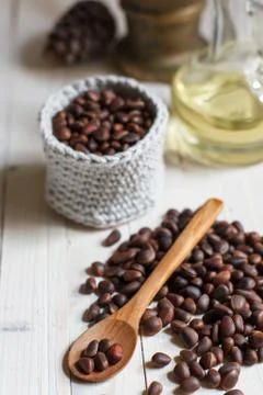 Unpeeled pine nuts in bulk on a table with a wooden spoon close-up Stock Photos