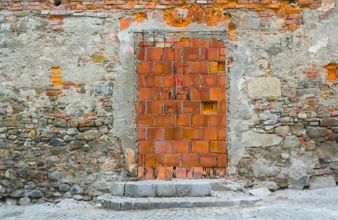 Unplastered stony wall with bricked up door. Stock Photos