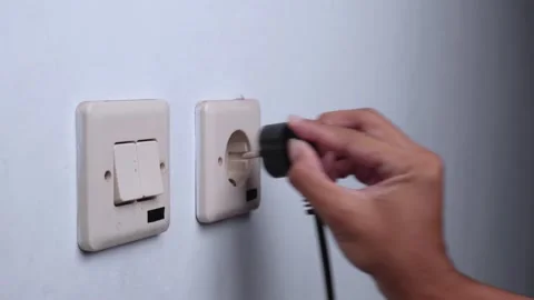 Unplugging the cable by hand from the wall outlet Stock Footage 274624411