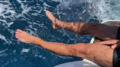 Unrecognisable man sitting on aft deck of sailing motorboat with legs put inside 스톡 동영상 318649255