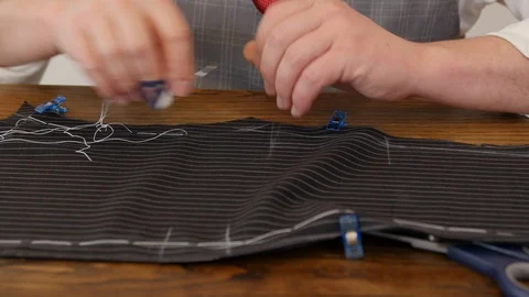 Unrecognisable man tailor hands stitch up cloth with basting tread a jacket of Stock Footage 127229710