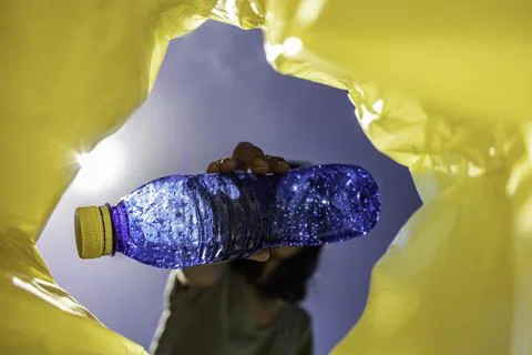 Unrecognisable woman recycling a blue plastic bottle Stock Photos