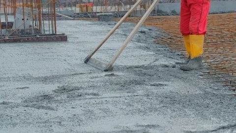 Unrecognised worker levelling concrete with a rake Stock Footage 102343744