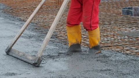 Unrecognised worker levelling concrete with a rake Stock Footage 102343761