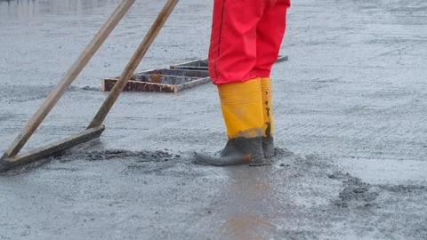 Unrecognised worker levelling concrete with a rake Stock Footage 102343772
