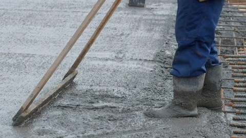 Unrecognised worker levelling concrete with a rake Stock Footage 102343790
