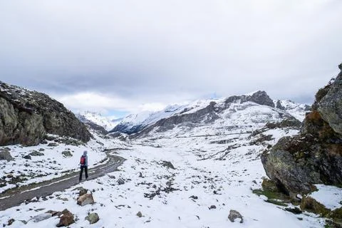Unrecognizable alone hiker with a red backpack walks along a snow-covered Stock Photos