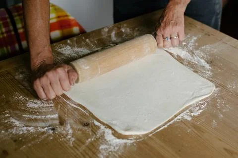 Unrecognizable baker rolling dough with pin on wooden table in daylight Stock Photos